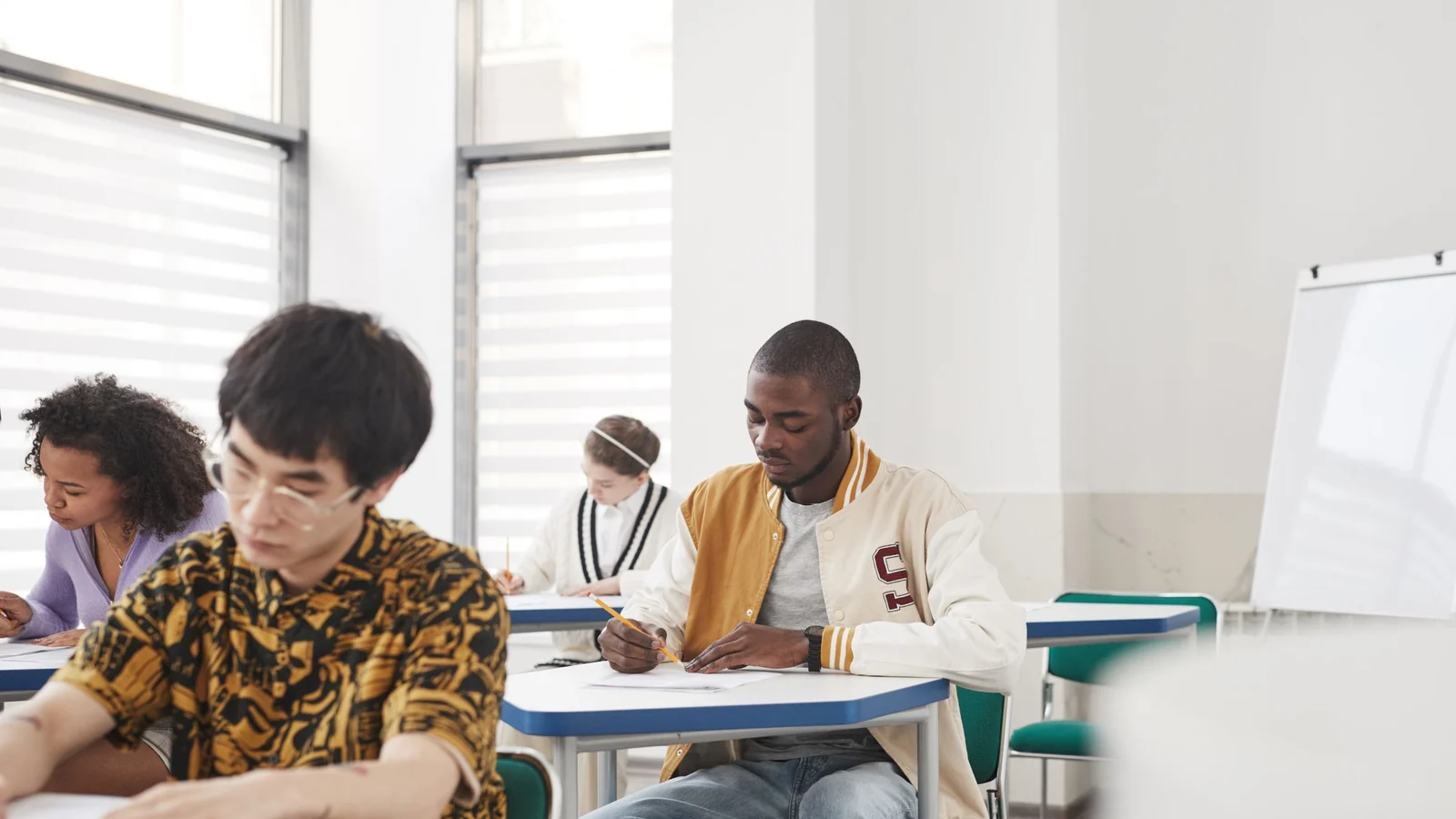 教室で英語力確認のテストを受ける学生