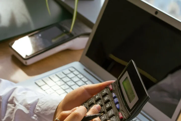 パソコンと電卓を使って費用項目を計算する手元