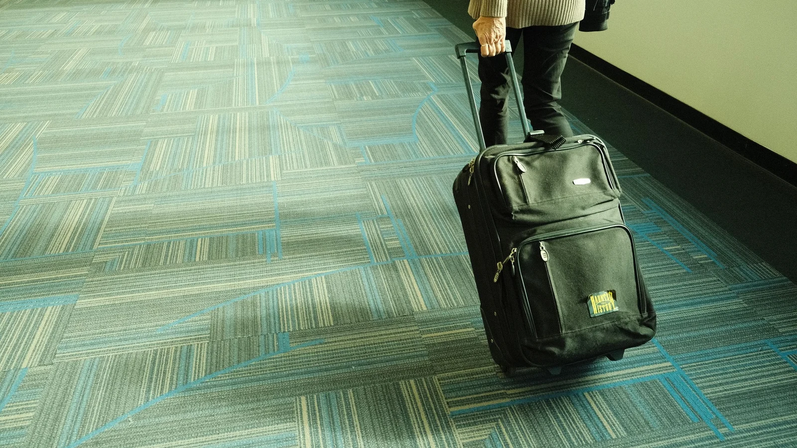 スーツケースを引いて空港通路を移動する旅行者