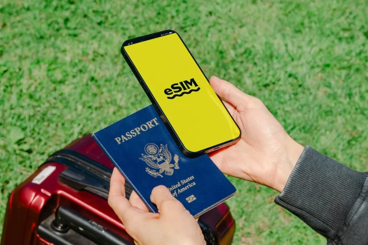 パスポートと荷物のそばでeSIM画面を確認する旅行者