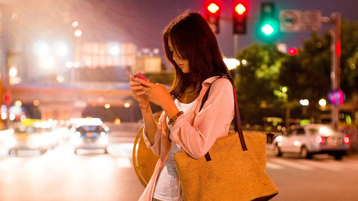 夜の通りでスマートフォンを見る人とかばん