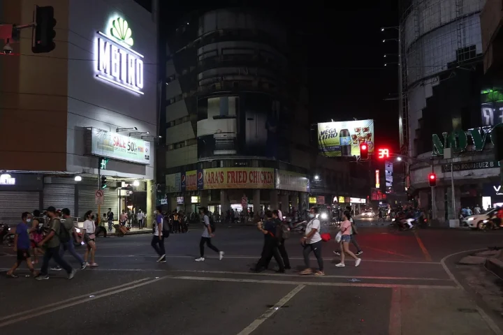 夜のマンゴー通りの交差点を渡る人たち