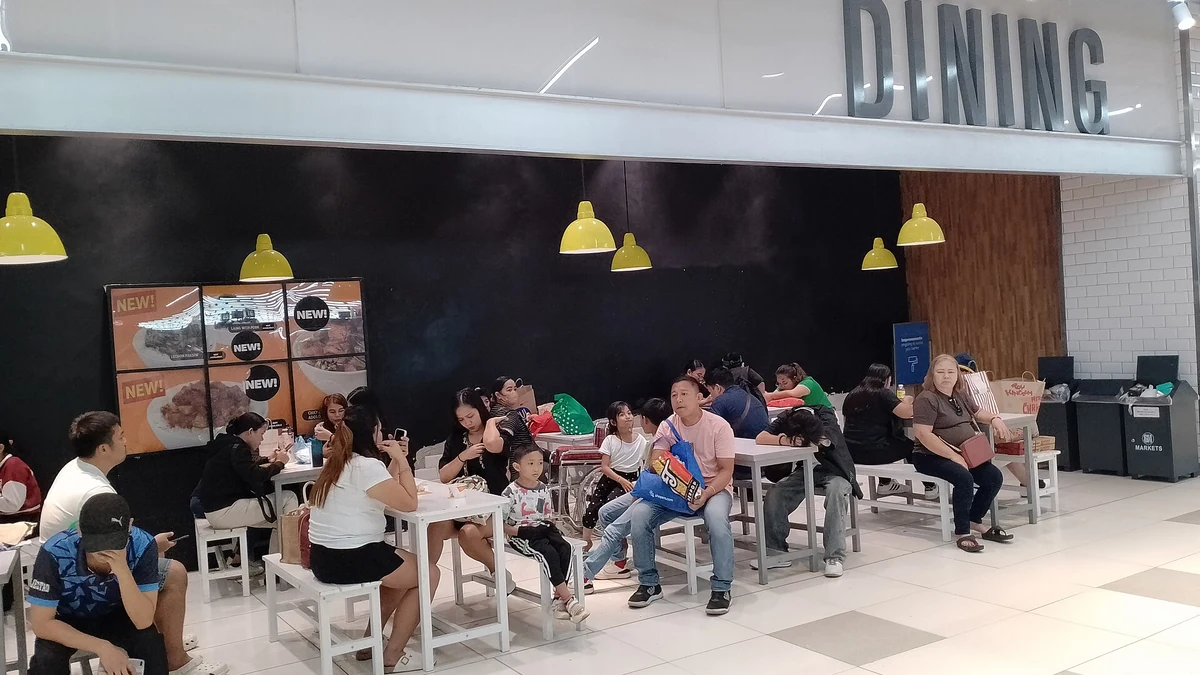 「DINING」の看板があるフードコートで食事をする人たち