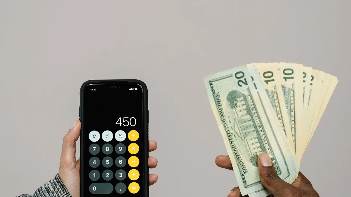 スマートフォンの電卓と米ドル紙幣(一般写真)