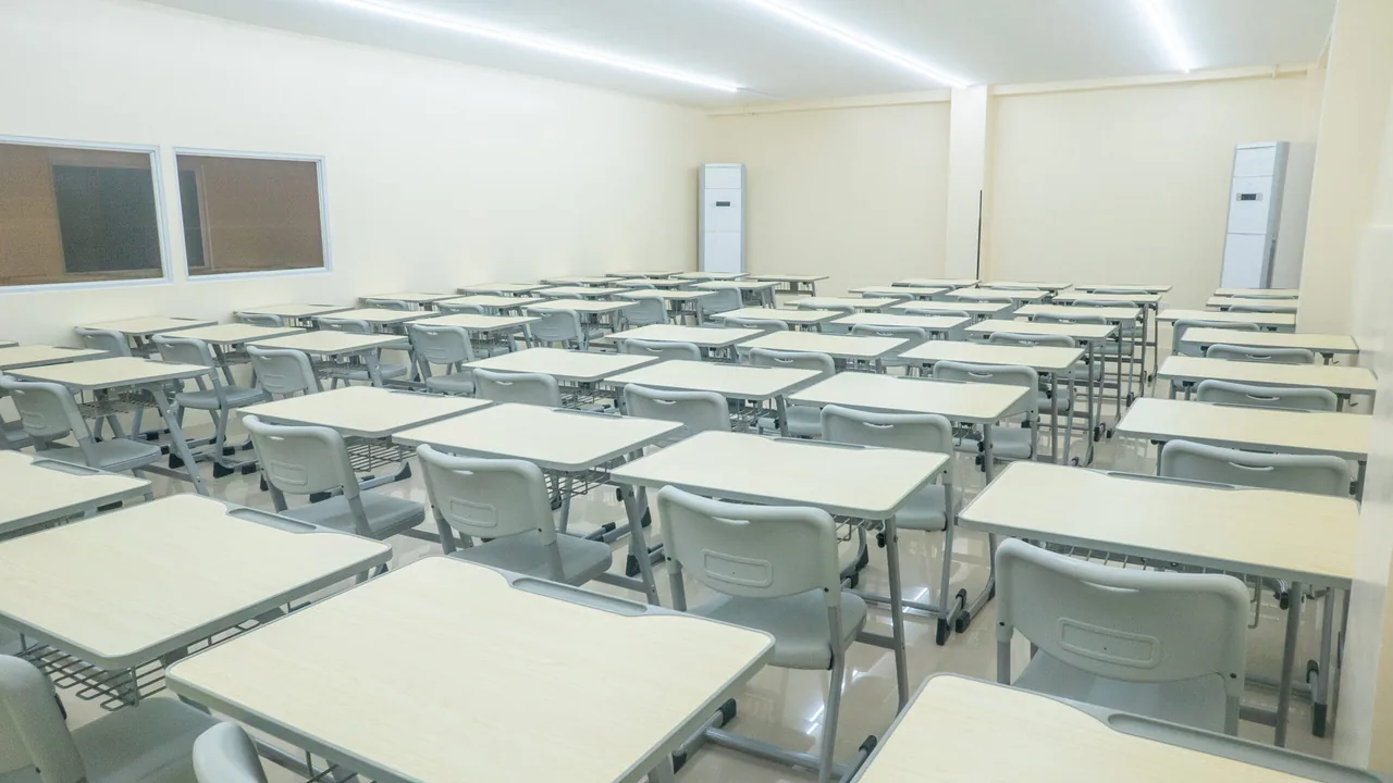机と椅子が整然と並ぶ、誰もいない明るい教室