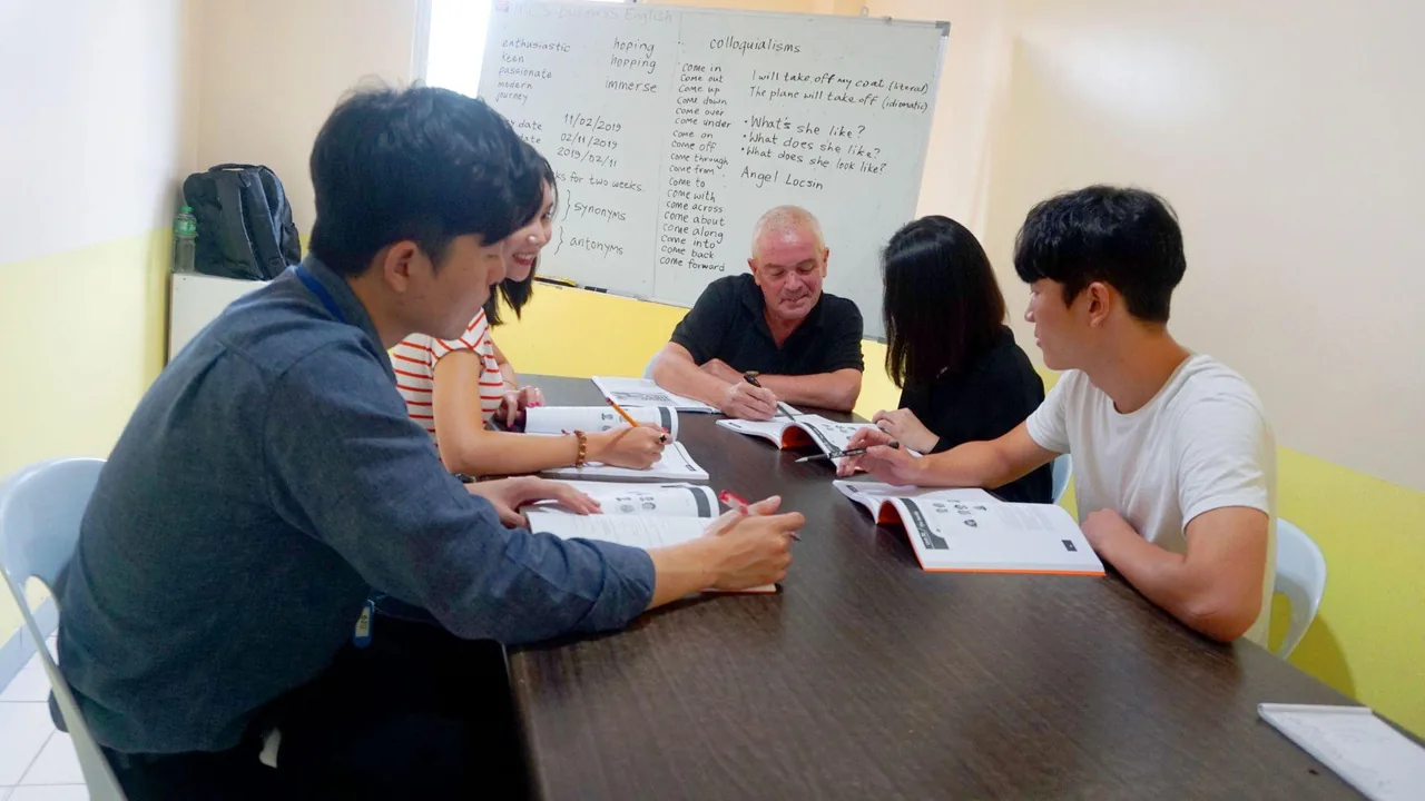 講師と生徒4人がテキストを広げて話す、少人数の英語の授業