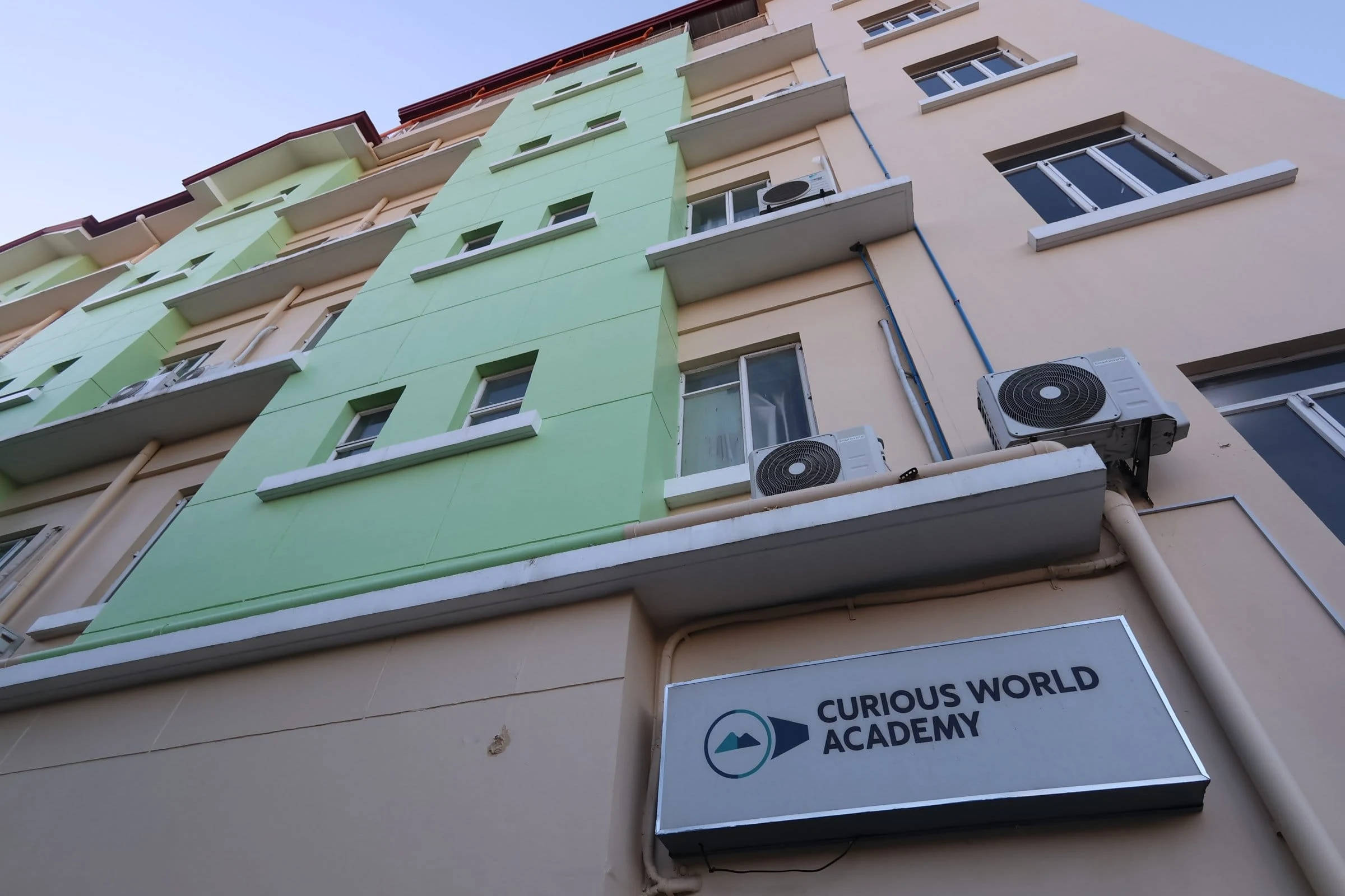 校舎の外壁に付いたCURIOUS WORLD ACADEMYの看板