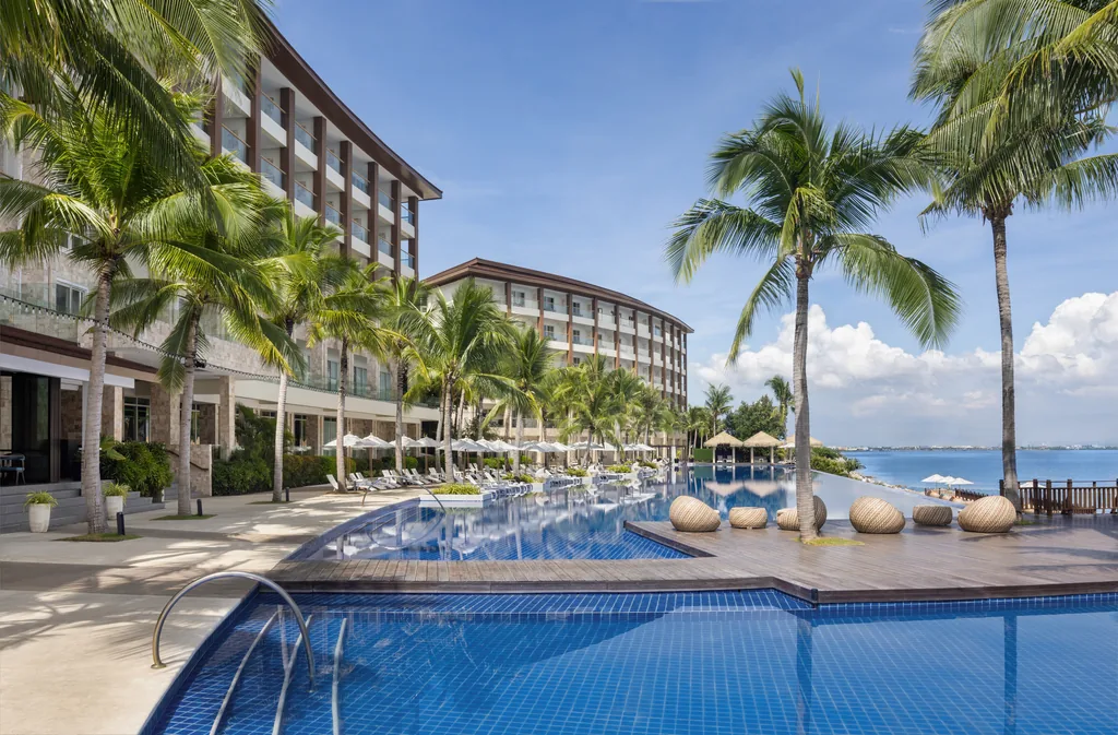 Dusit Thani Mactanのインフィニティプールと客室棟