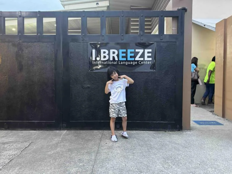六岁儿童站在I.BREEZE校门标志前