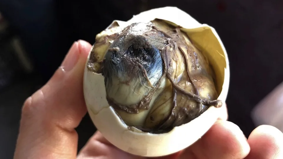 剥开蛋壳后的Balut，可看到熟蛋与鸭胚的形态。